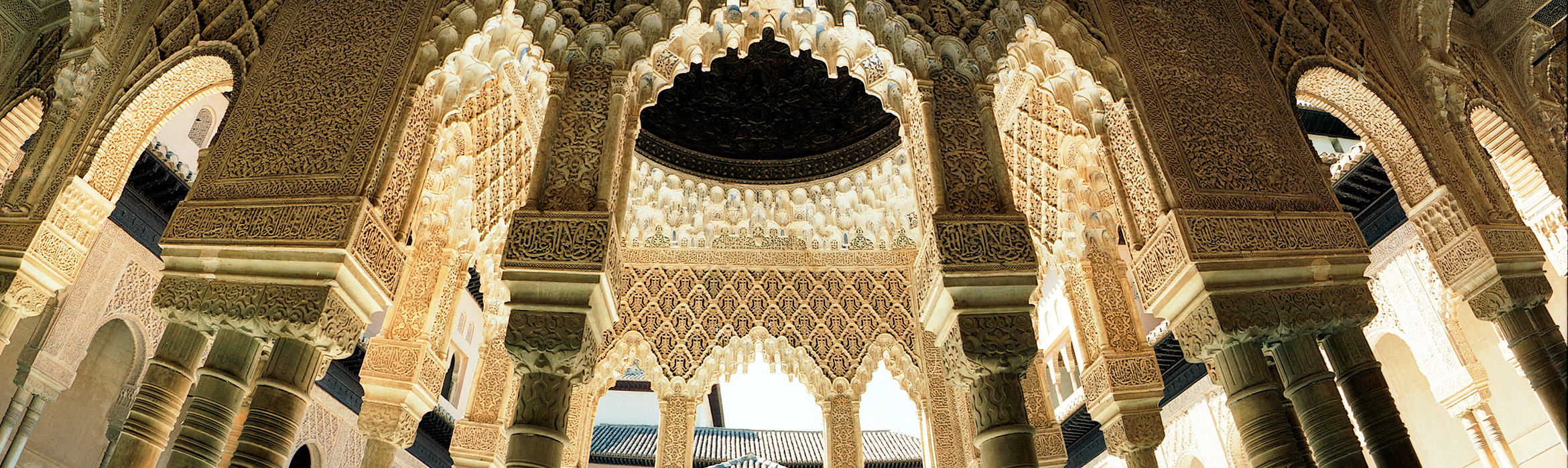 Imagen en la que se puede apreciar los arcos, las columnas y la decoración de la Alhambra.